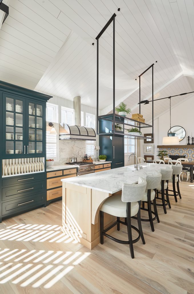 A spacious kitchen featuring a large island, elegant wooden floors, and stylish cabinetry and furniture. Contact Miller Cabinetry to start your project today!